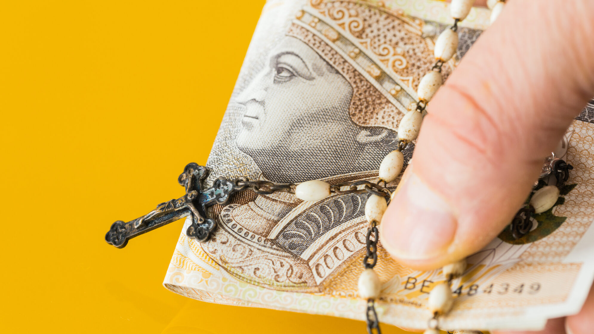 male_Christian,Rosary,Hand-held,With,Money.,Concept,Of,Church,Business,And